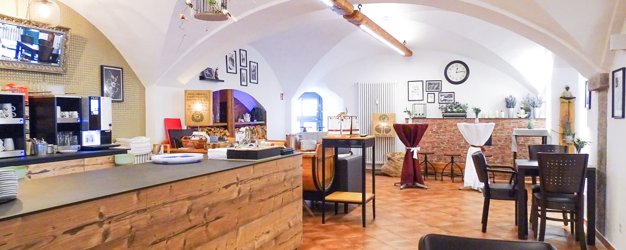 Café-Theke mit Kaffeemaschinen und gemütlichem Gastraum im Hintergrund