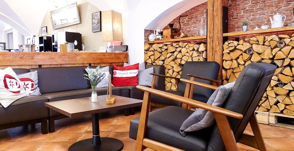 Sitzgruppe mit Sesseln und Sofa vor dekorativem Holzlager im Café
